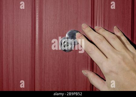 Una mano femmina apre la serranda sul peephole della porta anteriore. Il concetto di sicurezza e cautela. Foto Stock