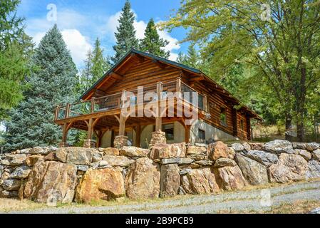 Un pittoresco rustico Home log in montagna circondata da alberi di pino su un colle roccioso in Coeur d'Alene, Idaho. Foto Stock