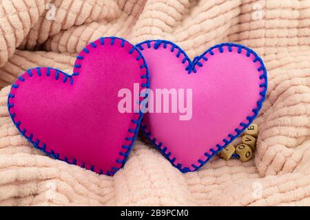 Mano cucito foglio di schiuma giocattolo cuori su uno sfondo rosa per romantico, relazione, San Valentino, cuore rotto amore concetto Foto Stock