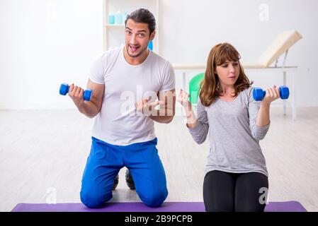 Donna che fa esercizi sportivi con allenatore personale Foto Stock