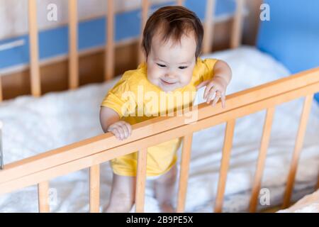 Ragazza felice con capelli scuri ridendo e sorridendo in giallo t-shirt gara mista kazako e tedesco in piedi nella culla della culla Foto Stock