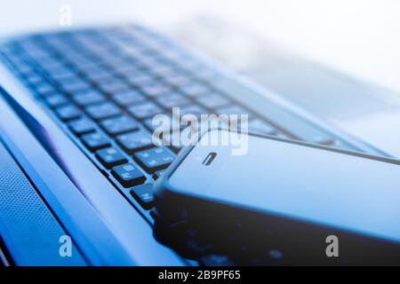 Immagine di primo piano di una tastiera con un telefono sopra di essa,messa a fuoco selettiva Foto Stock