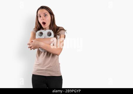 Giovane donna con rotoli di carta igienica su sfondo bianco. Shopping di panico Covid-19 Foto Stock