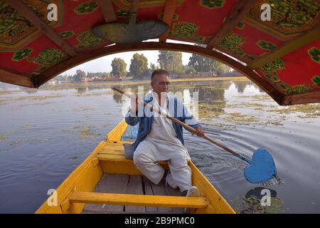 Un proprietario di Shikara che rotola il suo shikara o barca sul lago dal in Srinagar, Kashmir - India Foto Stock