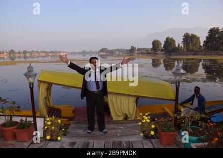 Un proprietario di casa galleggiante a Srinagar dietro è uno Shikara statico o una piccola barca nel lago dal di Srinagar, Kashmir Foto Stock