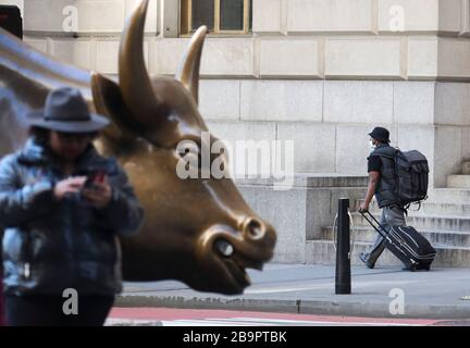 New York, New York, Stati Uniti. 24 Marzo 2020. New York, Stati Uniti. 24 Marzo 2020. Un uomo cammina oltre il Wall Street Charging Bull a New York, Stati Uniti, 24 marzo 2020. Il numero di casi COVID-19 negli Stati Uniti è stato superiore a 50,000 alle ore 3 (ora orientale degli Stati Uniti) di martedì (1900 GMT), secondo il Center for Systems Science and Engineering (CSSE) della Johns Hopkins University. La nuova cifra ha raggiunto 50,206 con 606 morti, il CSSE ha detto. Lo stato di New York è diventato l'epicentro dell'epidemia di COVID-19 nel paese, con 25,665 casi segnalati. Credito: Wang Ying/Xinhua/Alamy Live nuovo Foto Stock