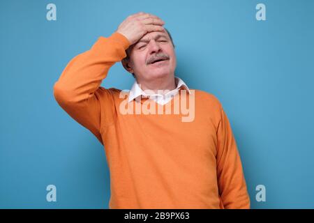 Uomo ispanico anziano che ha mal di testa e febbre come sintomo di influenza o coronavirus Foto Stock