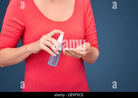 Donna matura disinfetta le mani con alcool contenente spray Foto Stock