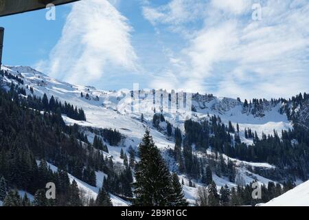 Piste innevate di Hoch Ybrig in Svizzera con vegetazione conifera di diverse dimensioni e cumulo e nuvole di circo sopra. Foto Stock