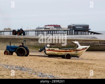 Crammer pescatore tirando in barca la spiaggia su rimorchio tirato da un trattore, Cromer, Norfolk, Regno Unito Foto Stock