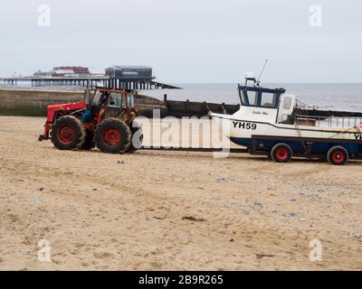 Crammer pescatore tirando in barca la spiaggia su rimorchio tirato da un trattore, Cromer, Norfolk, Regno Unito Foto Stock