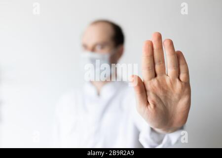 Virus maschera medico maschile indossare la protezione del viso nella prevenzione per coronavirus mostrando stop a mano Foto Stock