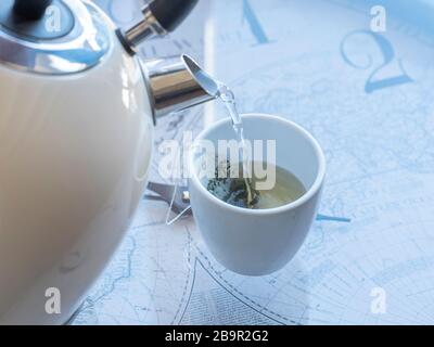 bollitore elettrico con acqua bollente per il tè alle erbe. Selettiva focalizzata su una tazza da tè con una borsa da tè Foto Stock