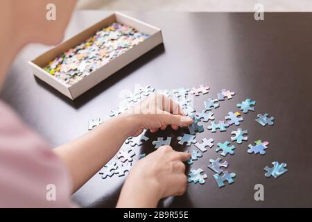 Auto-isolato signora senior giocare puzzle jigsaw a casa Foto Stock