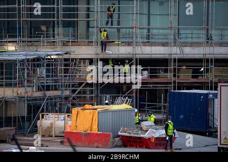 Lavoratori edili in un edificio residenziale a Canary Wharf, dopo che il primo ministro Boris Johnson ha messo il Regno Unito in blocco per contribuire a frenare la diffusione del coronavirus. Foto Stock