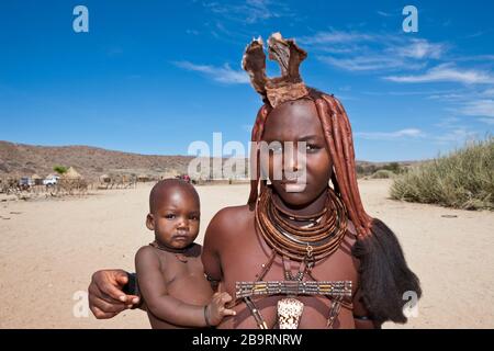 Himba Donna porta bambino, Damaraland, Namibia Foto Stock