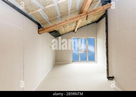 Rroom in costruzione con pannelli in gesso. Costruzione di tetti interni. Struttura della casa con telaio del tetto in legno. Foto Stock