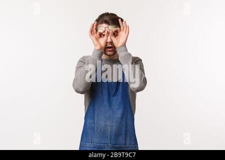 Ritratto di giovane uomo scioccato e stupito in grembiule, lavoratore del caffè strofinare gli occhi da incredulità, fissando impressionato e startled a qualcosa Foto Stock