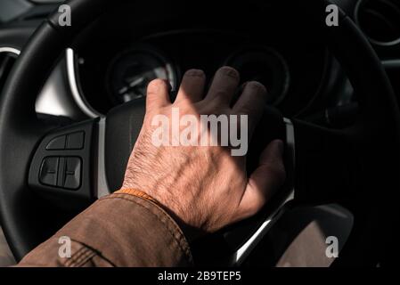 Honking l'avvisatore acustico del veicolo in ingorgo stradale, primo piano di mano maschio sul volante del veicolo con messa a fuoco selettiva Foto Stock