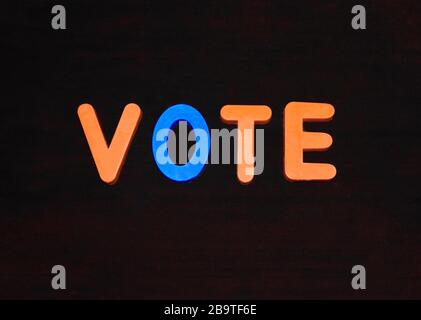 Parola di voto scritta con diversi blocchi di lettere colorati disposti su uno sfondo scuro Foto Stock