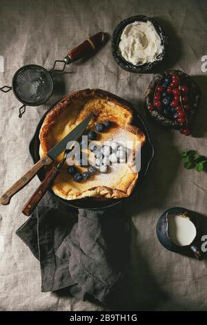 Freschi di forno olandese frittella di bambino in ghisa pan servita con blackberry e rosse bacche Ribes, il mascarpone, lo zucchero in polvere, brocca di crema, vintage Foto Stock