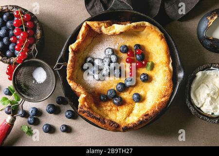 Freschi di forno olandese frittella di bambino in ghisa pan servita con blackberry e rosse bacche Ribes, il mascarpone, lo zucchero in polvere, brocca di crema, vintage Foto Stock