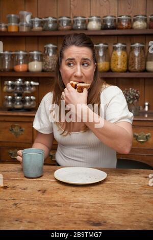Una donna nei suoi 30 anni che mangia una fetta di torta Foto Stock
