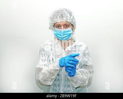 Donna che indossa una maschera protettiva per il viso, un copritesta e un abito all'interno del reparto ospedaliero Foto Stock