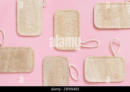 Vista dall'alto del layout composto con spazzolini da denti di bambù organici e spugne per il lavaggio dei piatti su sfondo rosa Foto Stock