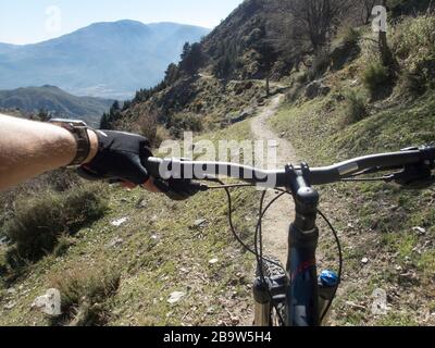 Una mano maschile sul manubrio di una mountain bike su un sentiero nella valle di Alpujarra tra Cañar e Lanjaron, Granada, Andalusia, Spagna Foto Stock