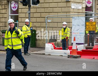 Leith, Edimburgo, Scozia, Regno Unito. 25 marzo 2020. Tram per i lavori di costruzione di Newhaven: Alcuni operai continuano a lavorare su Constitution Street nonostante l'appello del governo scozzese per i lavori di costruzione di cessare durante la pandemia di Coronavirus di Covid-19 Foto Stock