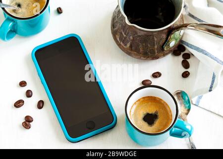 Tazze di caffè e cellulare sul tavolo Foto Stock