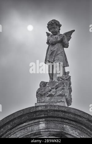 Immagine verticale in scala di grigi di un angelo scolpito a New Orleans Cimitero Foto Stock