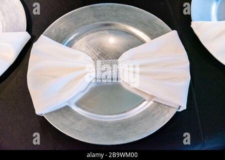 Primo piano ad alto angolo di un arco in raso bianco una piastra d'argento Foto Stock