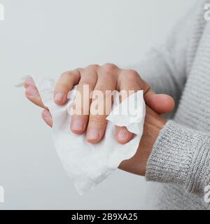 vestirsi di un uomo caucasico, indossando un maglione casual grigio chiaro, disinfettando le mani con una salvietta bagnata Foto Stock