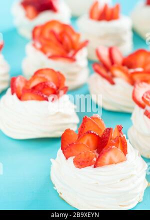 Belle torte Pavlova con fragole su sfondo blu. Messa a fuoco selettiva. Matrimonio mattina. Meringa con crema. Foto Stock