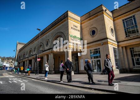 La gente si accoda fuori da un supermercato Waitrose a Bath, Somerset, dopo che il governo britannico ha annunciato severe restrizioni per cercare di controllare Coronavirus. Foto Stock