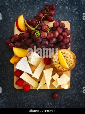 Formaggi, crecker e frutta su sfondo ligneo Foto Stock