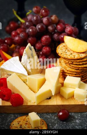 Formaggi, crecker e frutta su sfondo ligneo Foto Stock