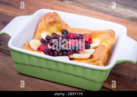 Pancake tedesco olandese sormontato con frutti di mirtilli e banana colazione al tavolo Foto Stock