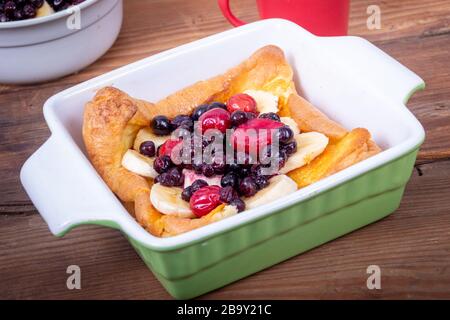 Pancake tedesco olandese sormontato con frutti di mirtilli e banana colazione al tavolo Foto Stock