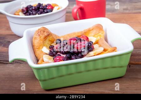 Pancake tedesco olandese sormontato con frutti di mirtilli e banana colazione al tavolo Foto Stock