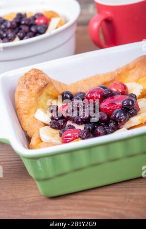 Pancake tedesco olandese sormontato con frutti di mirtilli e banana colazione al tavolo Foto Stock