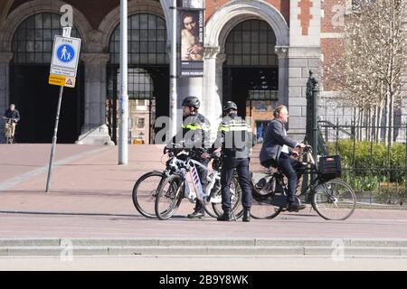 Amsterdam, Paesi Bassi. 25 Marzo 2020. Due poliziotti olandesi pattugliano le persone per praticare le distanze sociali e mantenere 1.5 metri al Museumplein il 25 marzo 2020 ad Amsterdam, Paesi Bassi. Il ministro olandese della giustizia e della sicurezza Ferdinand Grapperhaus ha ordinato nuove misure più severe per combattere la diffusione del coronavirus, nei parchi, nelle strade e negli spazi pubblici, la gente deve praticare il distanziamento sociale e mantenere 1.5 metri, questo per un gruppo di tre o più persone (che non sono familiari), Una multa di 400 euro sarà consegnato.(foto di Paulo Amorim/Sipa USA) credito: Sipa USA/Alamy Live NE Foto Stock