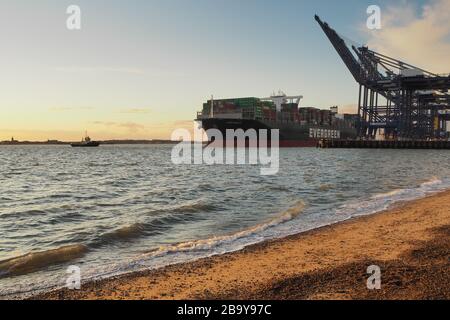 Porto di Felixstowe, Suffolk, Regno Unito, marzo 8 2020: La nave container è stata trainata dal molo al tramonto Foto Stock