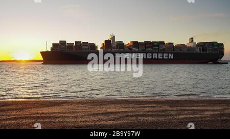 Porto di Felixstowe, Suffolk, Regno Unito, marzo 8 2020: La nave container sempre dolce con il sole tramontare su prua e rimorchiatore Foto Stock