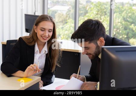 Due giovani uomini d'affari, uomini e donne Dew, lavorano in ufficio con felicità Foto Stock