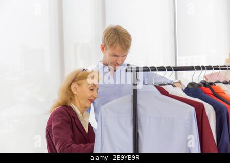 Le più anziane designer femminili consigliano abiti da uomo nei negozi di cucito Foto Stock