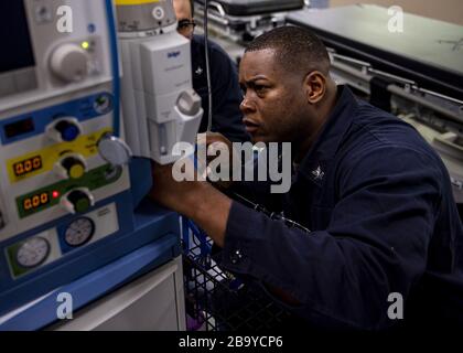 Los Angeles, California, Stati Uniti. 25 Marzo 2020. Ospedale Corpsman 2a classe Alton Gibbs, da Dothan, Ala., ricollega tubi ad una macchina per anestesia a bordo della nave militare Sealift Command ospedale USNS Mercy (T-AH 19) il 24 marzo 2020. Mercy è stata impiegata a sostegno degli sforzi di risposta del COVID-19 della nazione e fungerà da ospedale di riferimento per pazienti non COVID-19 attualmente ammessi in ospedali a terra. Ciò consente agli ospedali della base costiera di concentrare i propri sforzi sui casi COVID-19. Una delle missioni del Dipartimento della Difesa è il sostegno alla Difesa delle autorità civili. DoD sta supportando il Fe Foto Stock