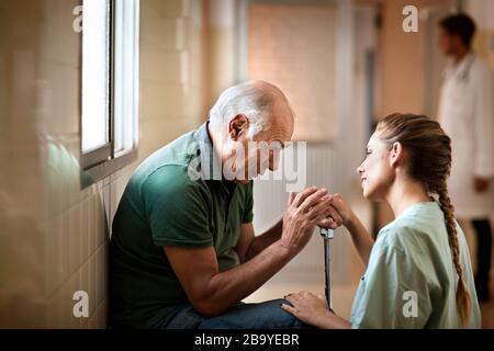 Senior uomo ricevere cattive notizie da parte di un infermiere. Foto Stock